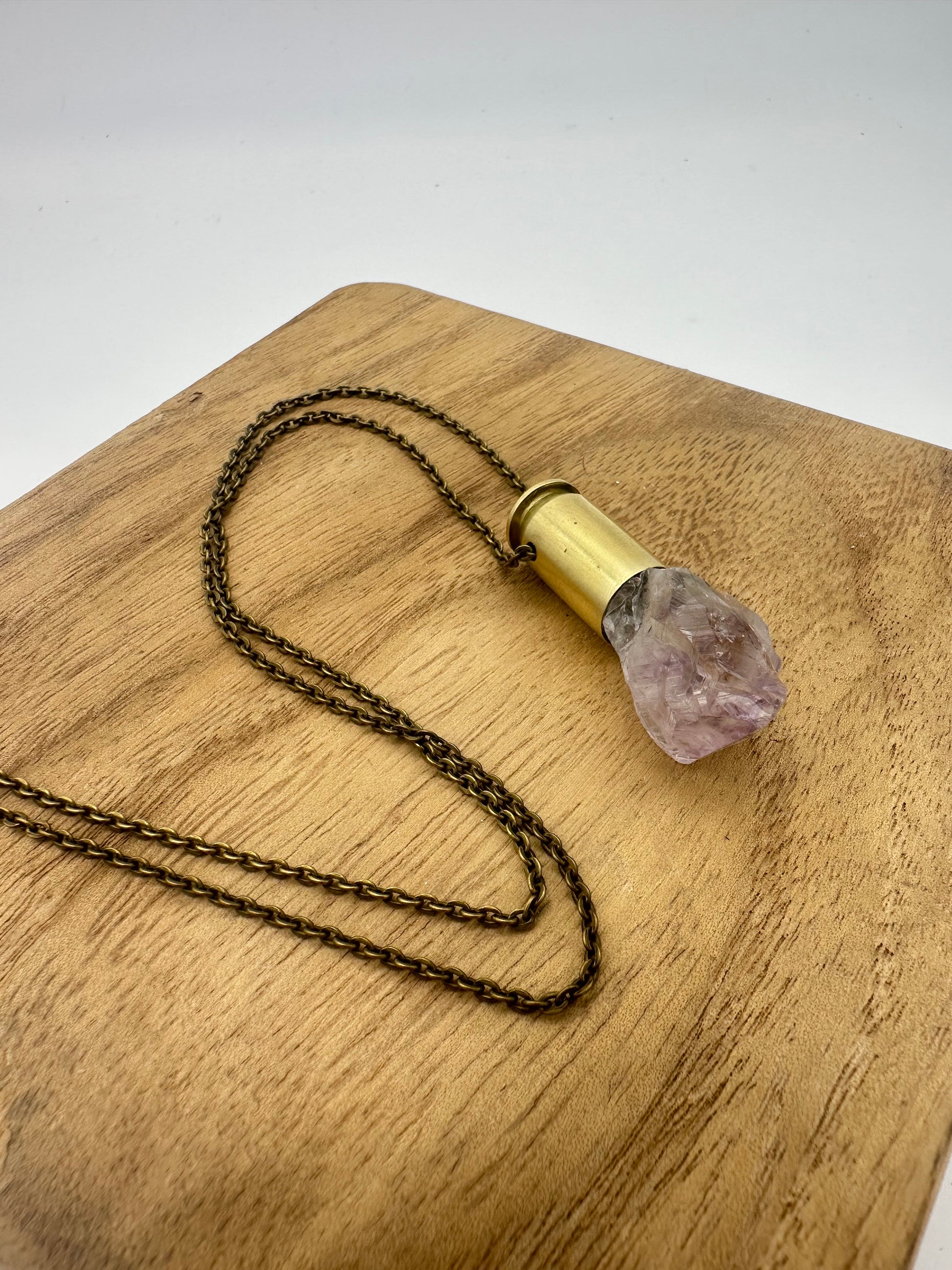 Reclaimed .45 bullet casing paired with raw amethyst point, handcrafted jewelry pendant