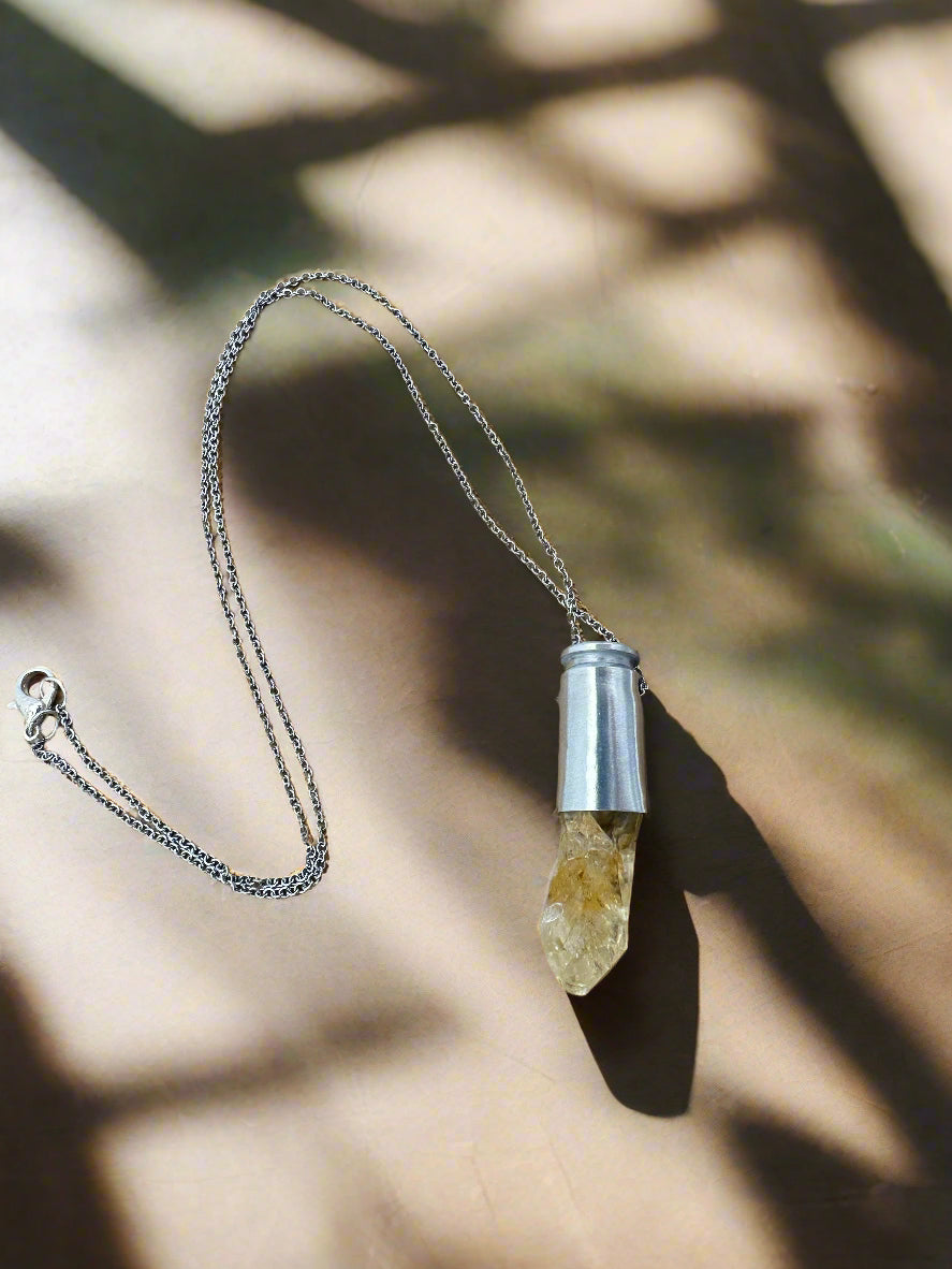 Crystals & Casings necklace featuring upcycled 40 caliber silver casing with golden citrine crystal point on 20-inch steel chain
