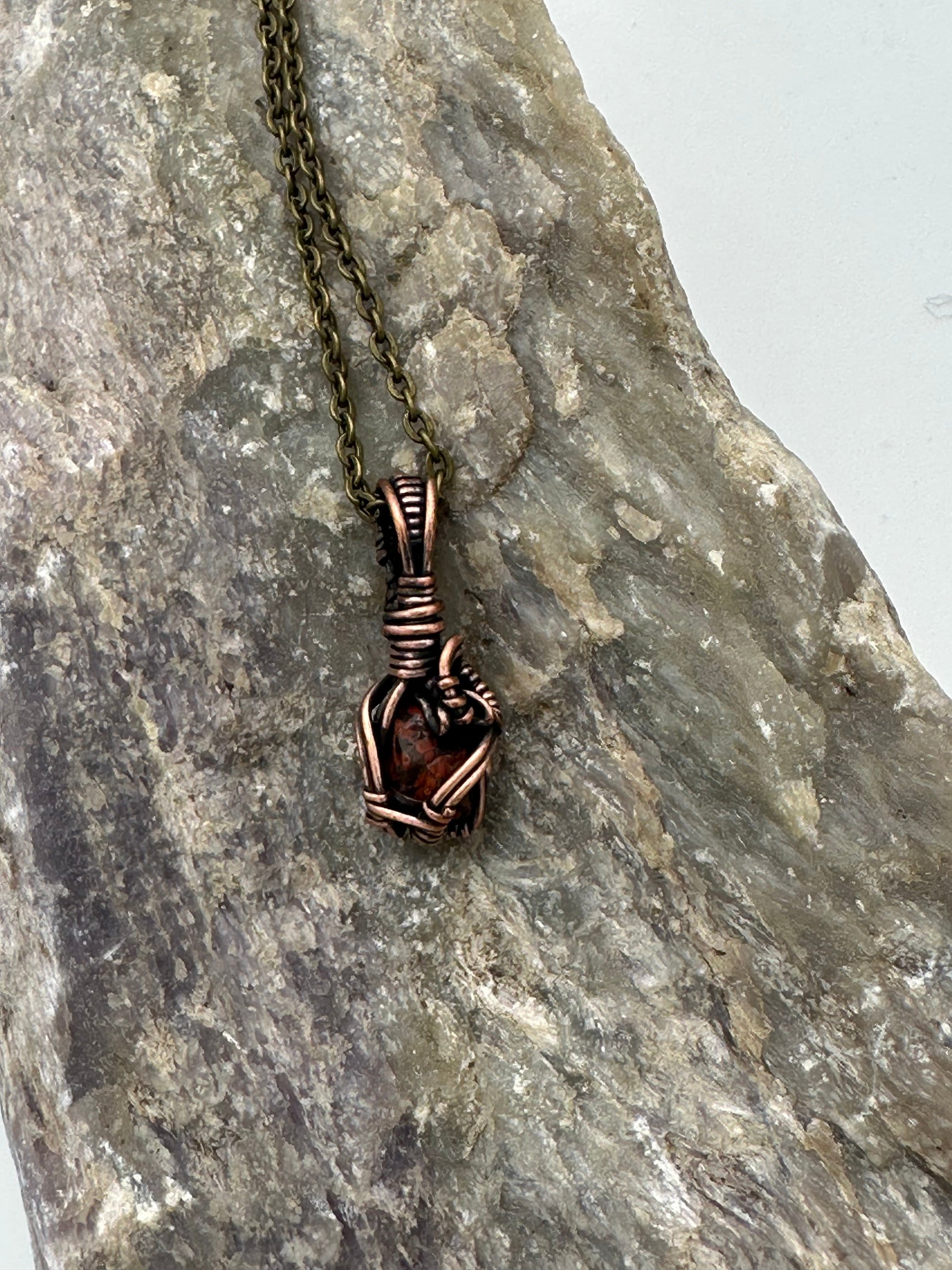 Bronze necklace with a unique pendant on a textured stone surface