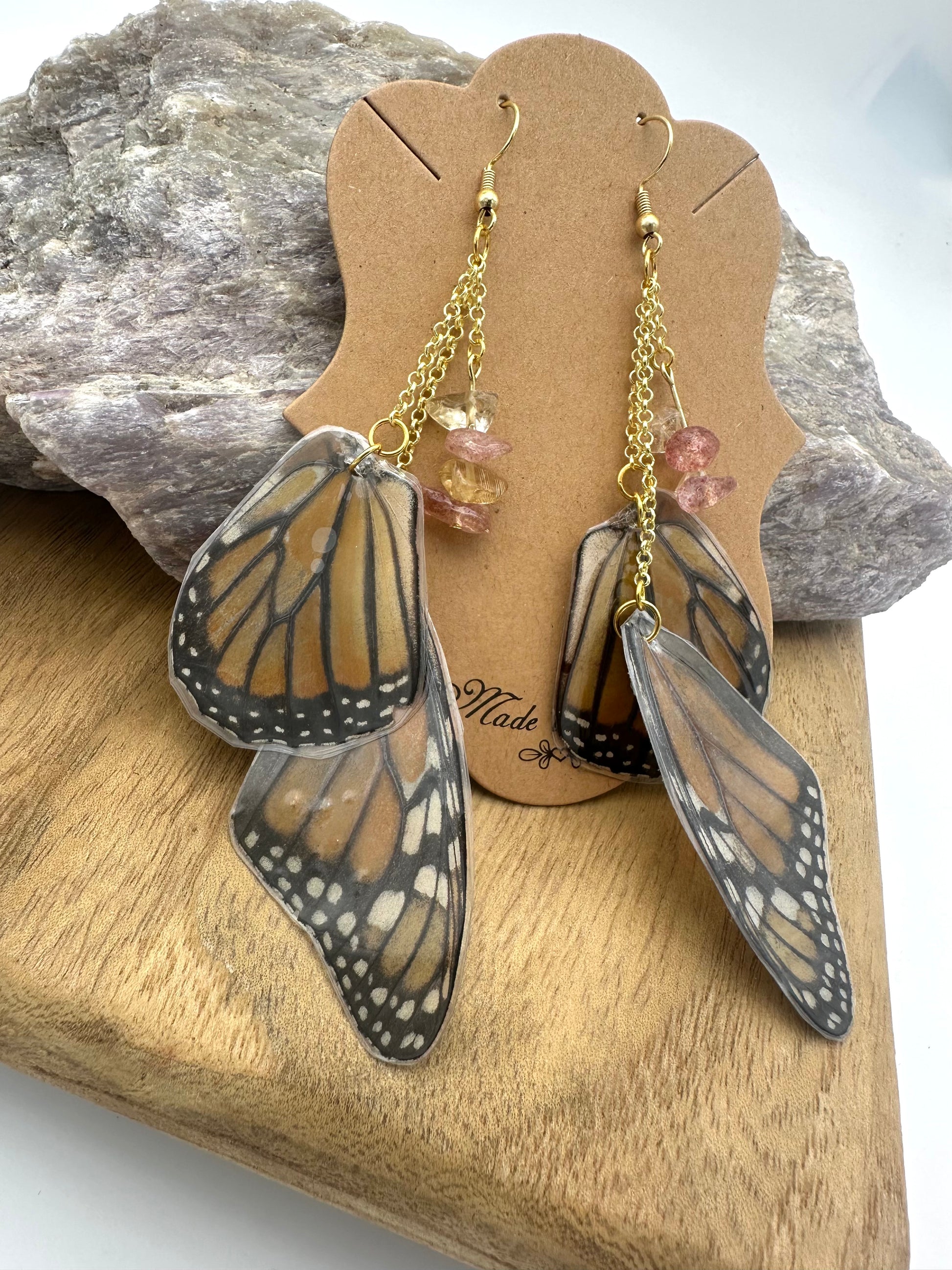 Close-up of handmade Monarch butterfly wing jewelry with orange-and-black preserved wings and pink Strawberry Quartz gemstones.