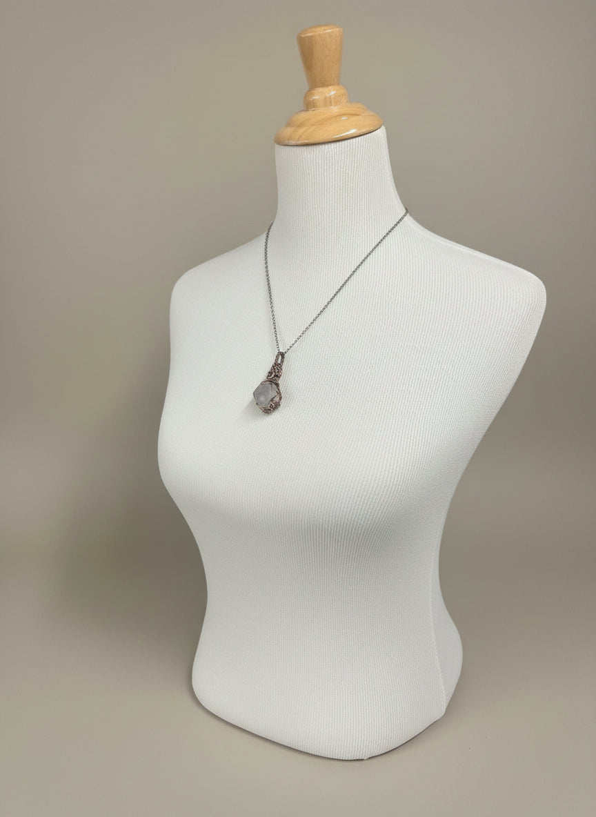 Necklace with a pendant on a mannequin against a patterned fabric background