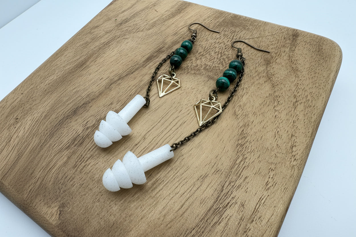 Pair of earplugs with green beads and gold geometric charms on a wooden surface