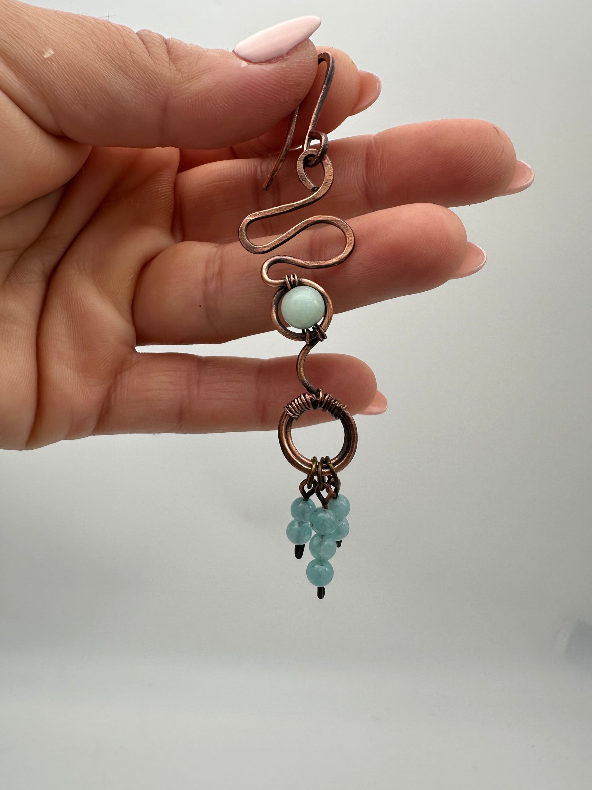 Hand holding a decorative keychain with beads against a plain background