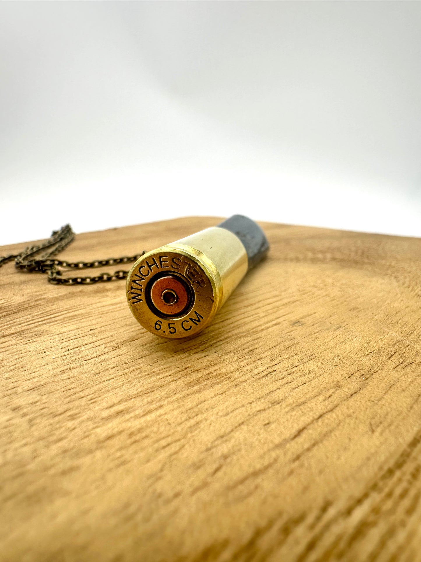 Angle-cut Winchester 6.5 bullet casing paired with raw kyanite crystal, handcrafted jewelry pendant