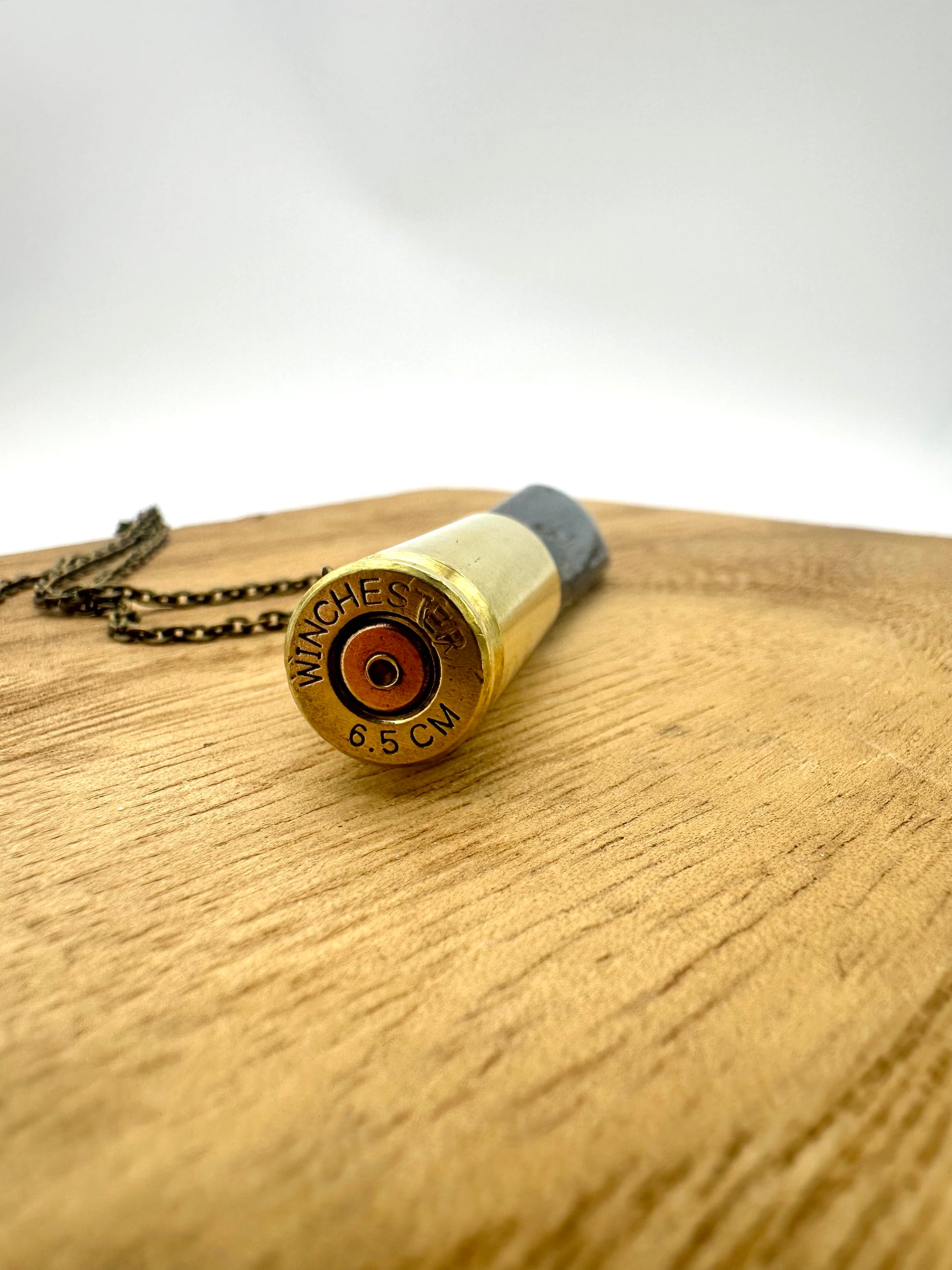 Angle-cut Winchester 6.5 bullet casing paired with raw kyanite crystal, handcrafted jewelry pendant