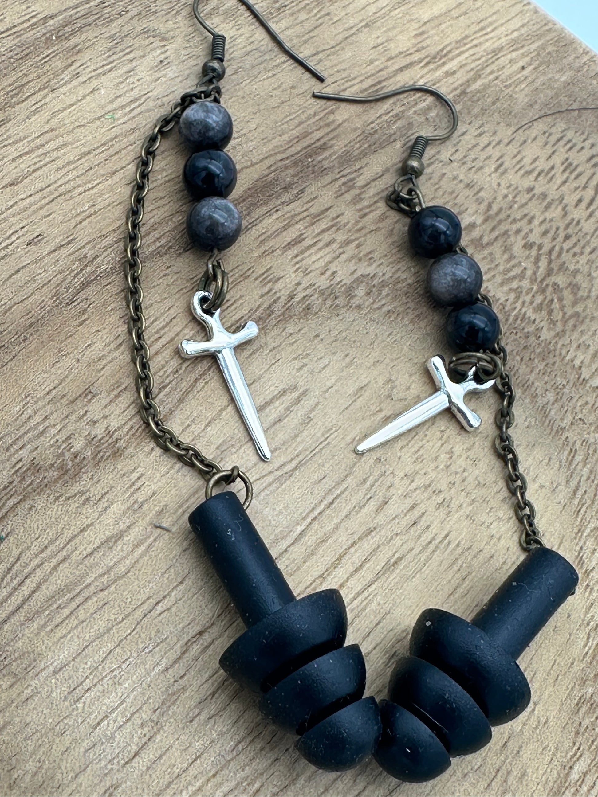Black beaded earrings with cross charms on a wooden surface