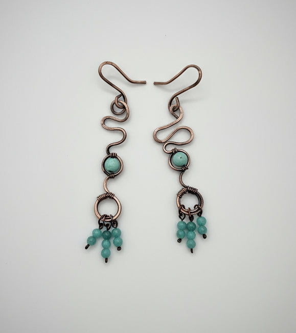 Pair of copper earrings with turquoise beads on a white background