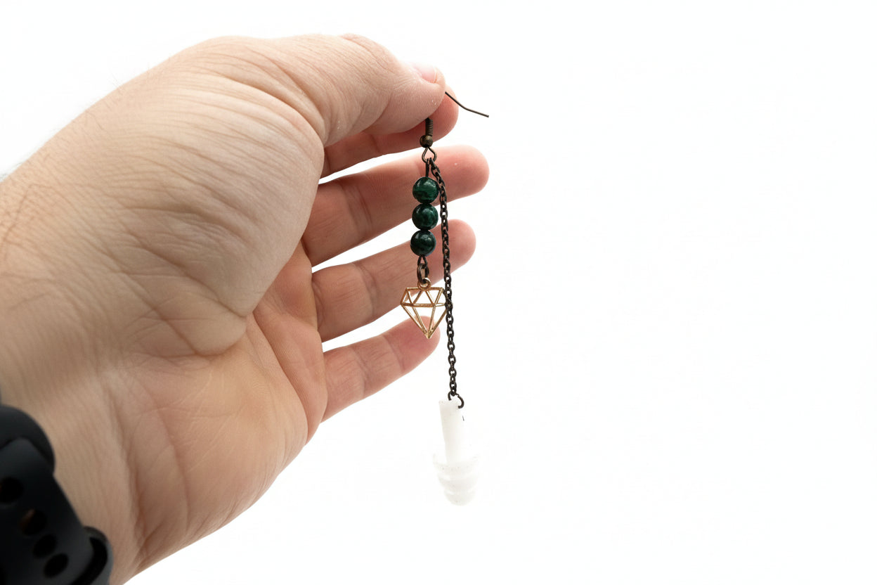 Hand holding a small decorative item with beads and a geometric design against a plain background