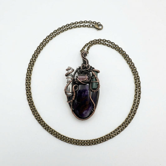 Necklace with a large purple stone pendant on a textured beige surface