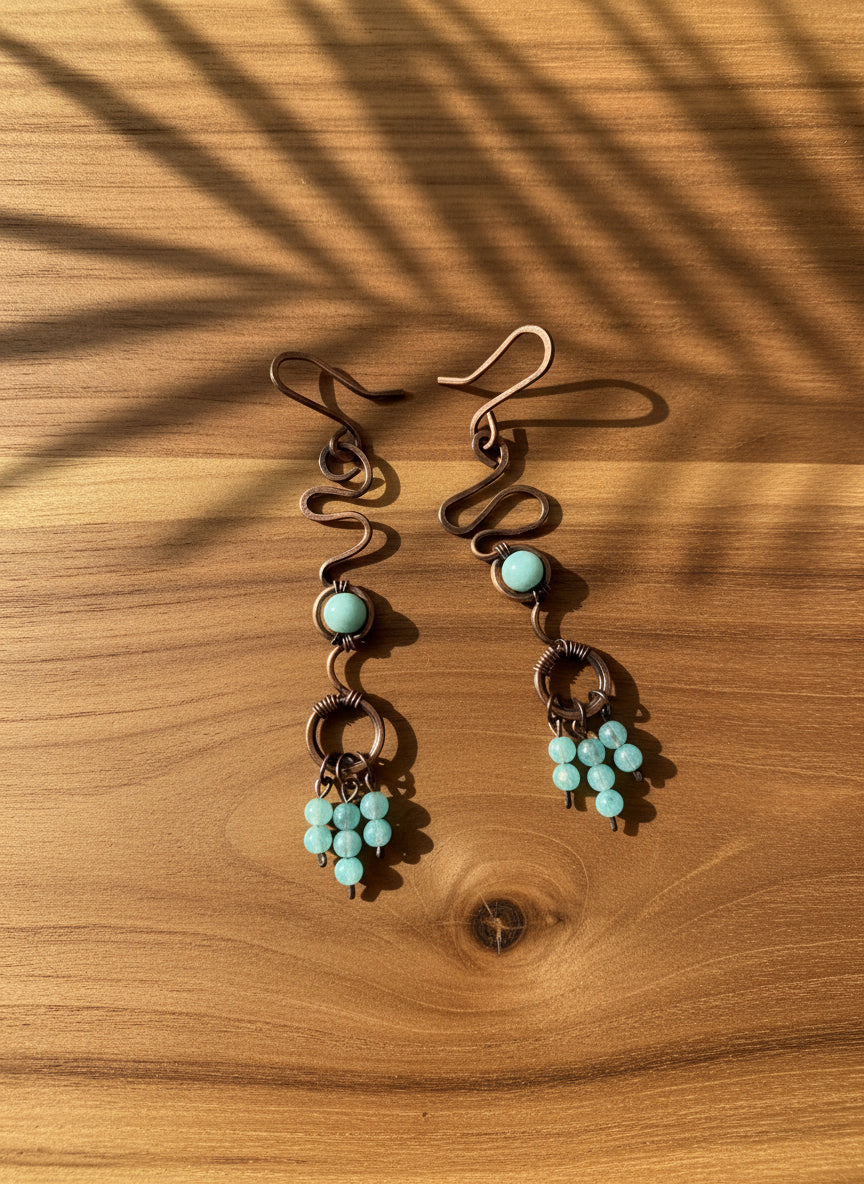 Pair of copper earrings with turquoise beads on a white background