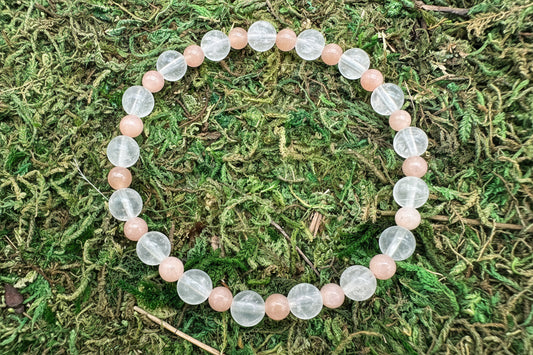Beaded bracelet with clear and pink beads on a green moss background
