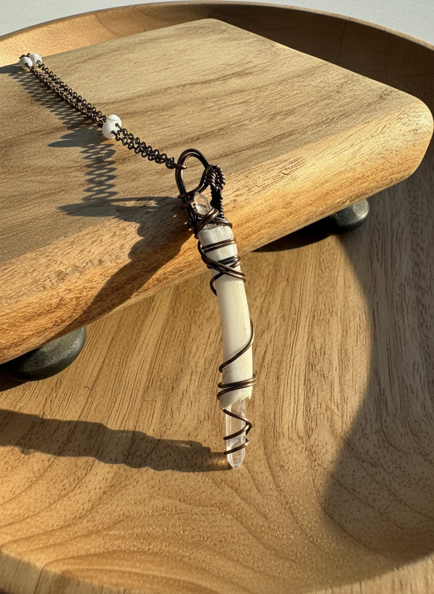 Front view of a copper-wrapped deer bone and quartz pendant on a brass chain with howlite beads.