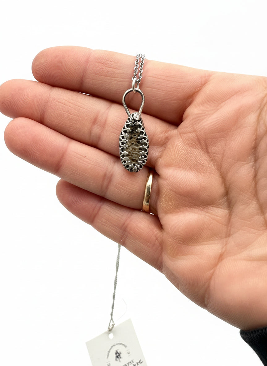 Sterling silver deer ribcage bone pendant shown in hand for size reference