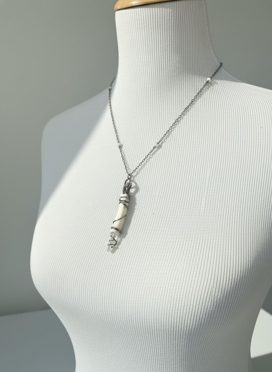 Silver necklace on a mannequin with a patterned fabric background