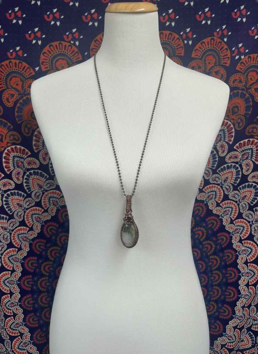 Dendritic agate and 3.62 carat garnet copper wire wrapped pendant displayed on necklace bust