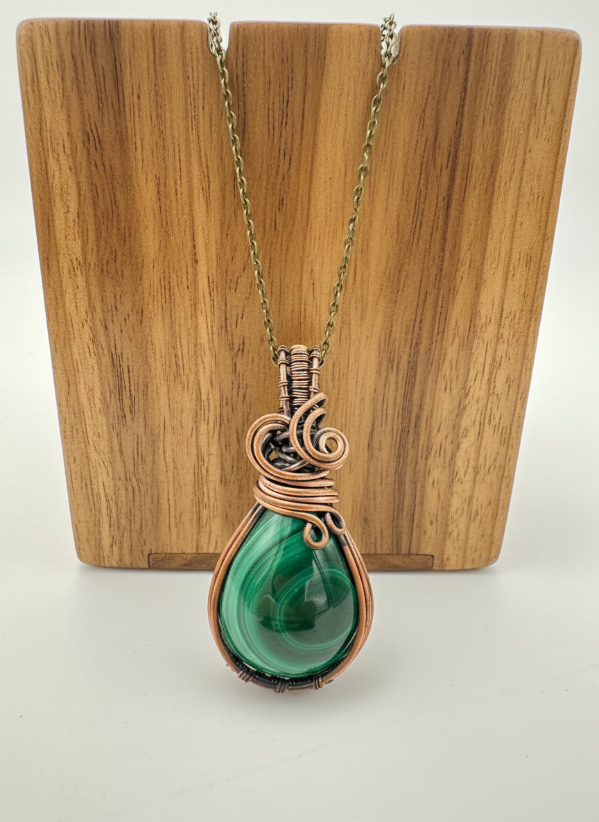 Close-up of natural malachite stone wrapped in copper wire with visible green banding