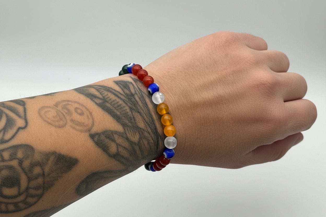 Multicolored beaded bracelet on a wrist with tattoos against a plain background