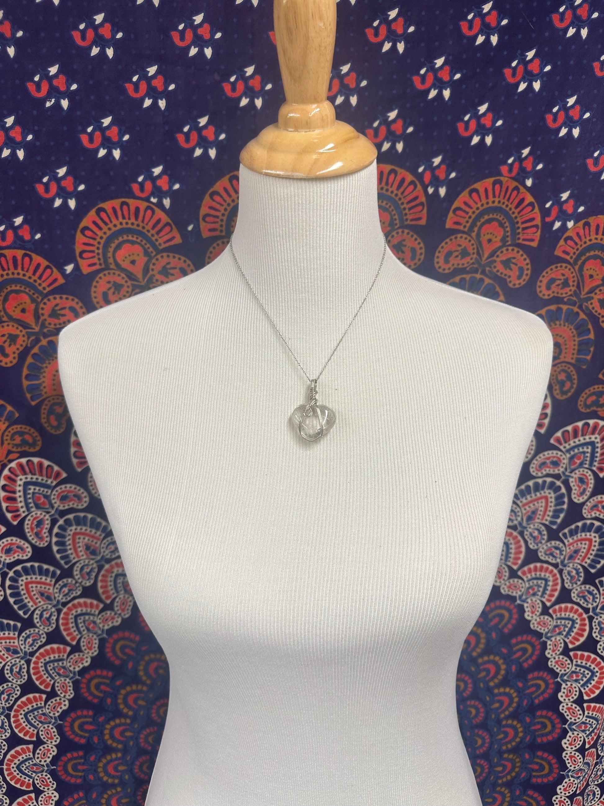 Heart-shaped quartz pendant wrapped in sterling silver displayed on necklace bust with 18 inch chain
