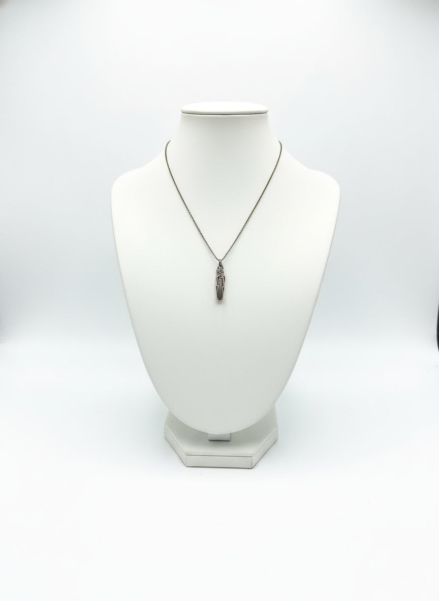 Red dinosaur bone pendant displayed on a necklace stand with copper wire wrapping and brass chain.