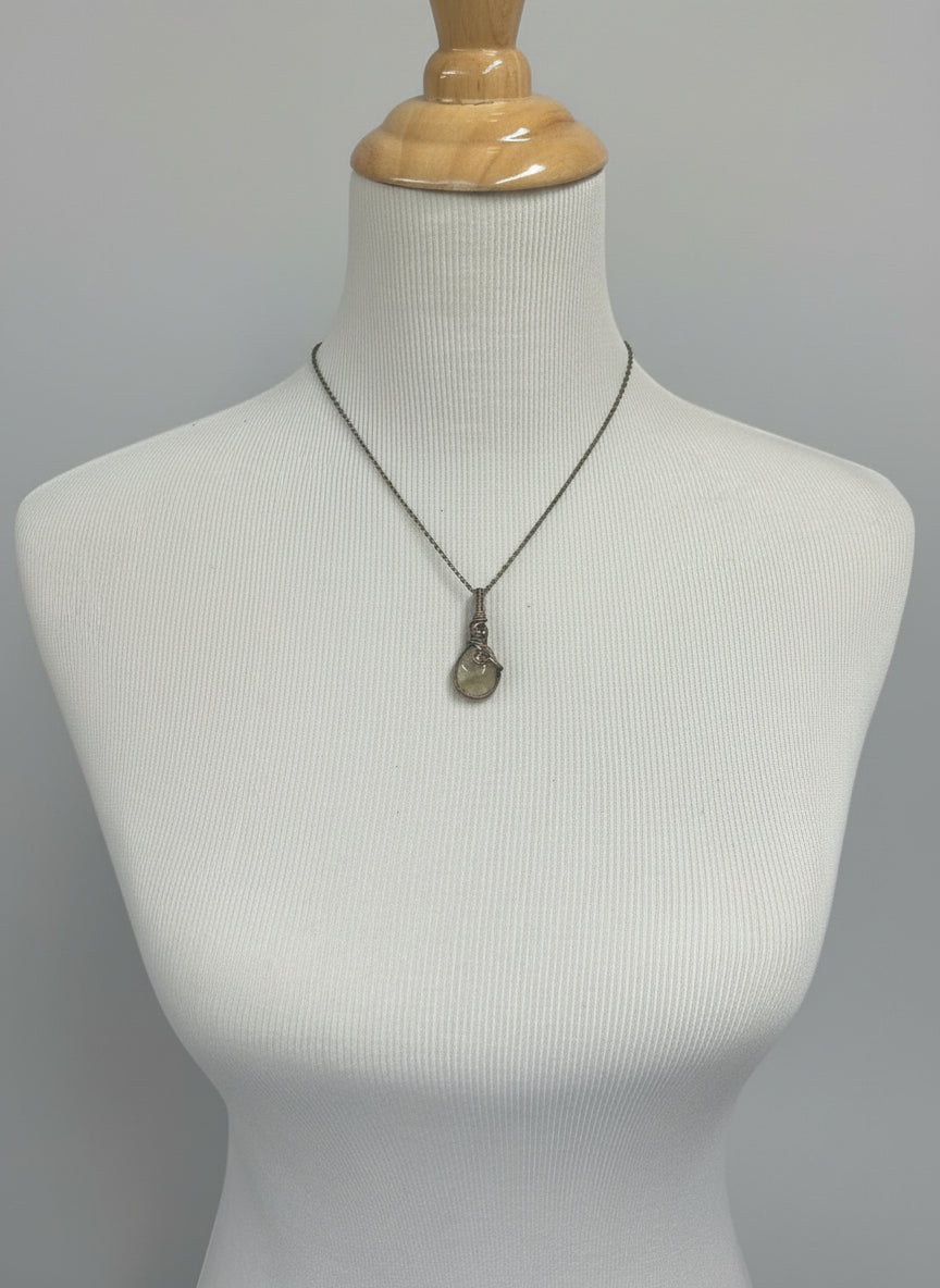 Golden rutile quartz pendant on an 18-inch brass chain displayed on a jewelry stand